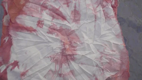 Hand pulling out red aniline dyed raw cloths with tie dye technique Video stock 141554547