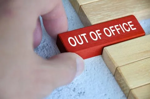 Hand pulling out a red wooden block with out of office text on. Getaway or .. Stock Photos