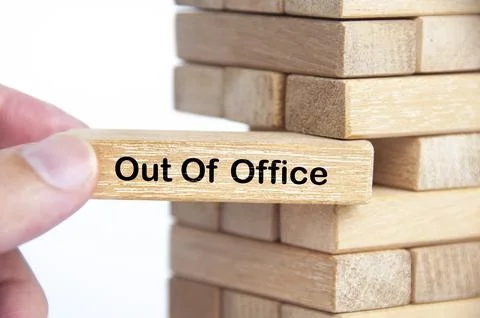 Hand pulling out wooden block with out of office text on it. Getaway or on .. Stock Photos