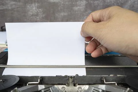 Hand pulling a piece of white paper from an old classic typewriter. Copy spac Stock Photos