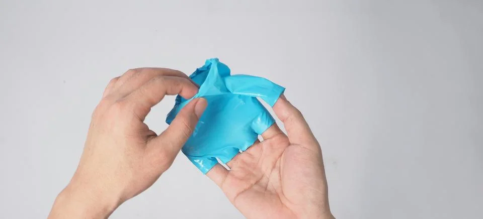 Hand is pulling right hand with blue latex gloves on white background. Stock Photos