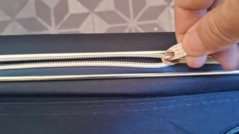 Hand pulling silver metal zipper slider on blue luggage video footage Stockbeeldmateriaal 339247311