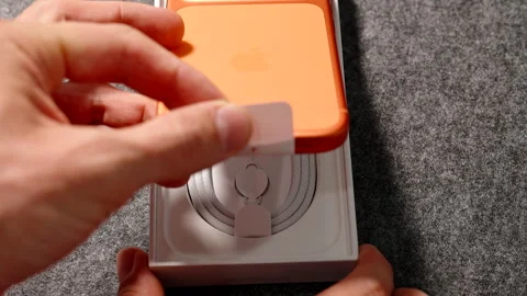 Hand Pulling Tab to Lift Cosmic Orange iPhone 17 Pro Out of Box with Visible Stock Footage 318057296