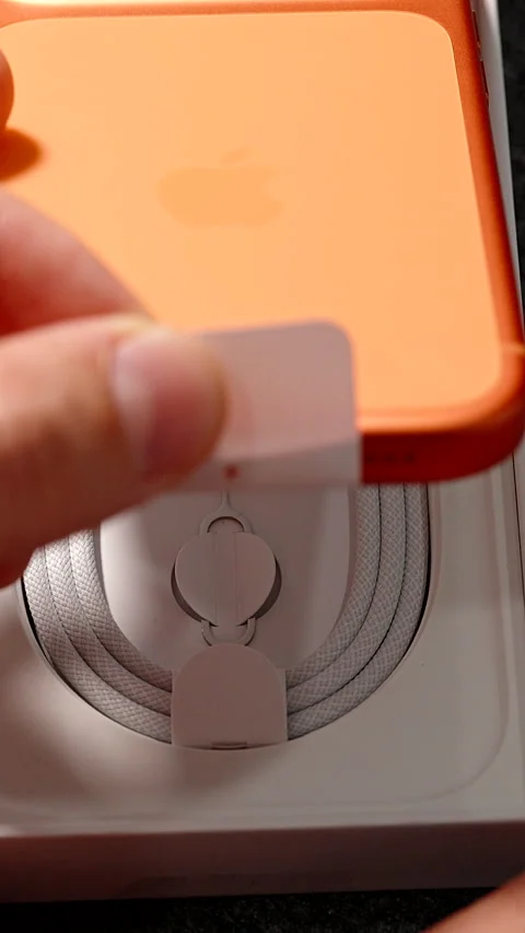 Hand Pulling Tab to Lift Cosmic Orange iPhone 17 Pro Out of Box with Visible Stock Footage 318057306