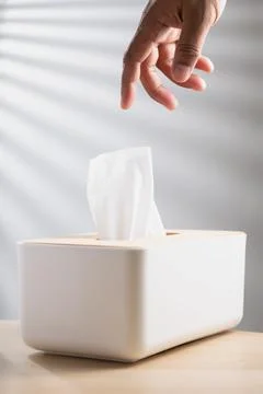 A hand pulling a tissue out of the white box Stock Photos