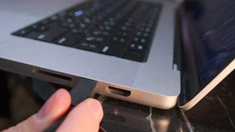 Hand pulling USB C cable out of laptop port, close-up of disconnecting device Stock Footage 333649734