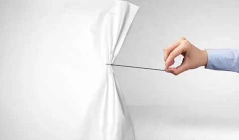 Hand pulling white paper curtain Foto stock