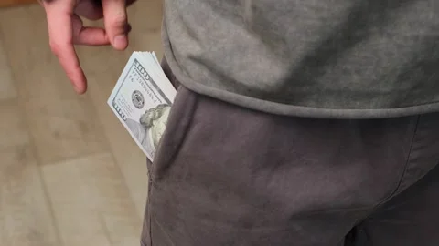 A hand pulls cash from a pocket, pointing at the money, representing bribery Stock-Footage 303903291