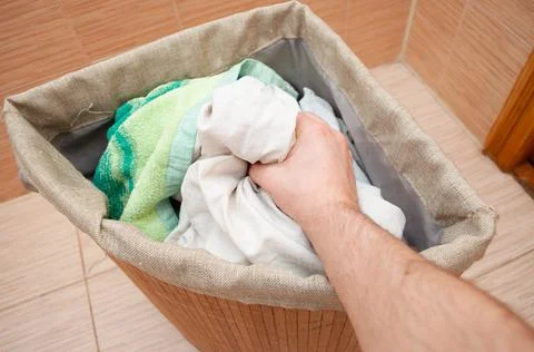 Hand pulls dirty clothes out of the laundry basket Stock Photos