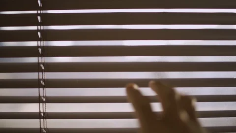 Hand pulls down venetian blinds to look outside the window Video stock 109164261