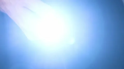 Hand Pulls Flashlight from Pocket Shining Bright Light into Camera Stock Footage 315773767