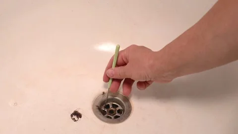 Hand pulls hair clog out of drain with metal tool. Stock Footage 337543271