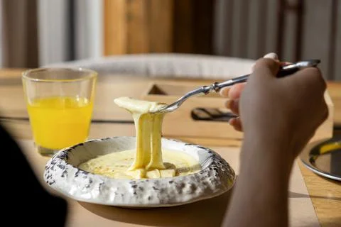 A hand pulls melted cheese from a bowl of creamy mashed potatoes with a met.. Stock Photos