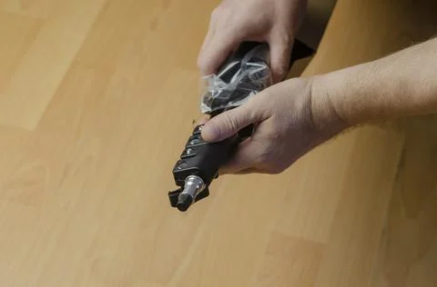 A hand pulls a new black softbox tripod in clear packaging out of a cardboard Stock Photos