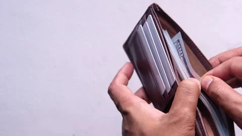 Hand pulls one hundred dollar bill out of brown leather wallet. Stock Footage 332579142