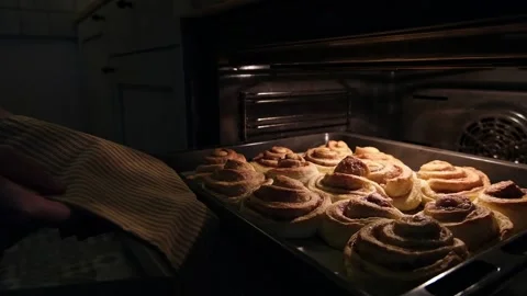 The hand pulls out a baking tray with muffins or buns from the oven Stock-Footage 221782119