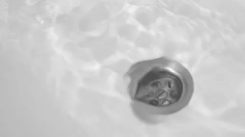 The hand pulls the rubber stopper from the sink, the water drains into the drain Stock Footage 156772561