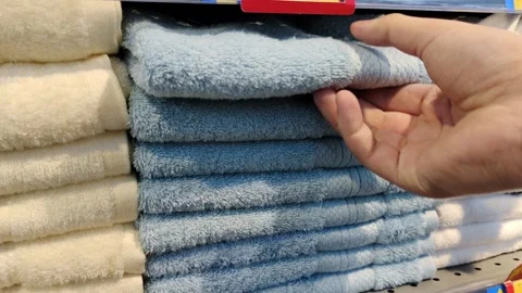 A hand that pulls a towel from a store display rack full of towels Video stock 304068834