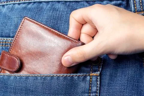 A hand pulls a wallet out of the back pocket of his jeans.The concept of pick Foto stock