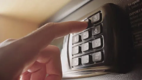 Hand punches code to open and lock security deposit box or safe in hotel room Stock Footage 197338019