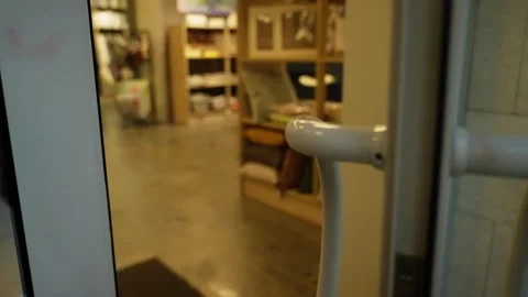 Hand pushes a circular white handle on a glass door to enter a cozy home goods Stock-Footage 327319886