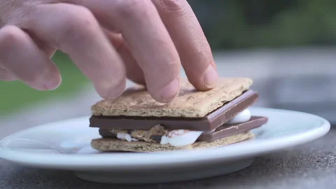 A hand pushes down the top of a s'more in slow motion Stock Footage 132510582