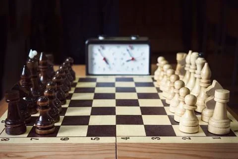 Hand pushing chess time clock. Playing quick chess with timer on dark background Stock Photos
