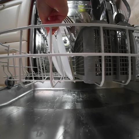 Hand pushing dirty dish rack into open dishwasher before washing cycle Stock-Footage 321819661
