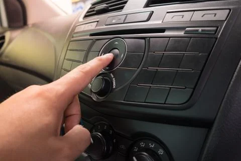 Hand Pushing the power button to turn on the car stereo system Stock Photos