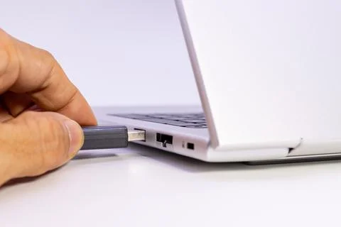 Hand pushing usb flash drive fully into laptop port showing secure hardware Stock Photos