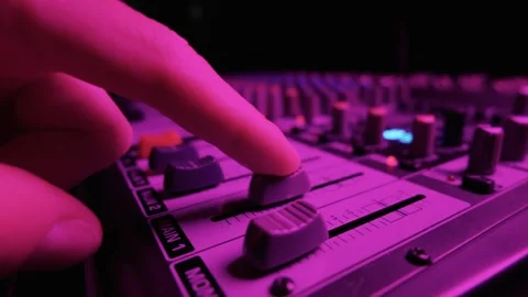 Hand Pushing Volume Fader on Audio Mixer Console in Bright Purple Light Stock Footage 334736604