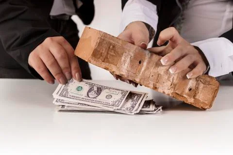 Hand put banknotes under the brick Stock Photos