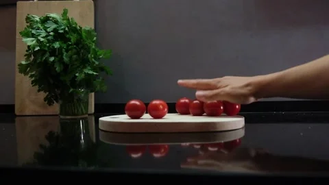 Hand put cherry tomato on cutting board in dark kitchen Stock Footage 242834503