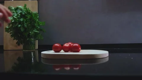 Hand put cherry tomato on cutting board in dark kitchen Stock Footage 242834647