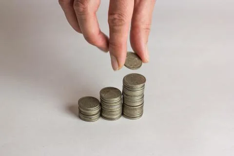 Hand put coins to stack of coins on white background Stock Photos
