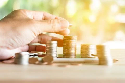 Hand put coins to stack of coins saving money and income or investment idea.. Stock Photos