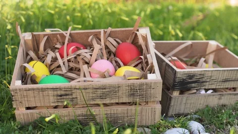 Hand put colored egg in box. two wooden box in the green spring grass. Stock-Footage 126281006