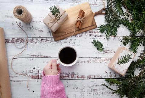 Hand put cup of coffee on the table with gifts Stock Photos