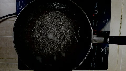 Hand put instant noodle into boiled water in teflon pan on electric stove, ,r Stock Footage 128941746