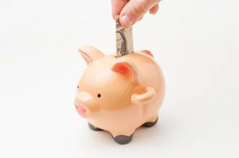Hand put a one dollar bill into a piggy bank Stock Photos