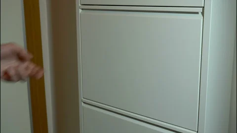 A Hand is puting shoes onto a Layered Mechanical Shoe Cabinet Stock Footage 129828717