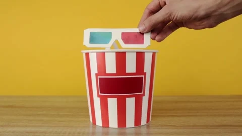 Hand puts 3d glasses on buckets with popcorn 库存影片 150402079