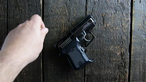 Hand puts ammo on wooden background Stock Footage 106936829