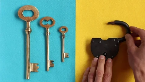 Hand puts black padlock on yellow, three vintage golden keys on blue felt, opens Video stock 88087521