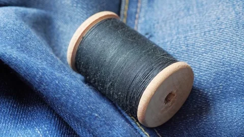 Hand puts black threads on blue denim close-up 動画素材 281503945
