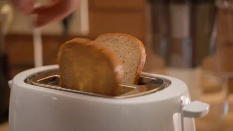 Hand puts bread in toaster and turns on toasting in kitchen Video stock 324698808