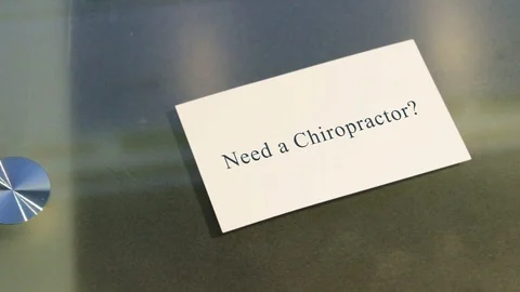 Hand puts business card on table with text Need a Chiropractor Stock Footage 71606757