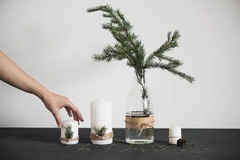 The hand puts a candle on the table. Chritmas decorations on tha table, spruc Stock Photos