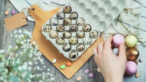 The hand puts a colored Easter egg on the table. The concept of preparing for Stock Footage 263239492