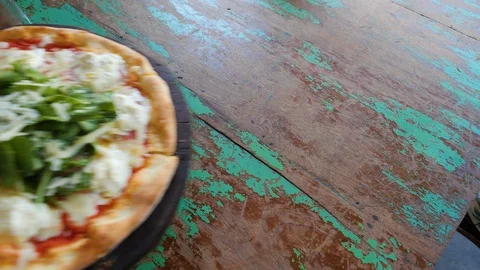 Hand puts fresh pizza on a rustic wooden table, Bali Vídeos de archivo 140253647